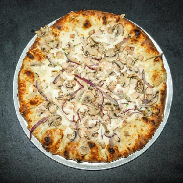 White pizza with chicken, mushrooms, and red onions on a metal tray.
